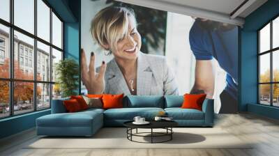 Coworkers working process at home.Young blonde woman working together with bearded colleague man at modern home office.People using electronic devices.Blurred background.Horizontal. Wall mural