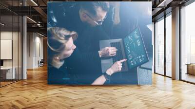 Coworking process in office.Two young colleagues using computer.Woman wearing black pullover and sitting on the sofa.Graphs,online interfaces and diagramm on laptop screen.Horizontal, visual effects. Wall mural