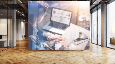 Young businessman analyze stock report on notebook screen.Concept of digital screen,virtual connection icon,diagram,graph interfaces on background.Double exposure. Wall mural