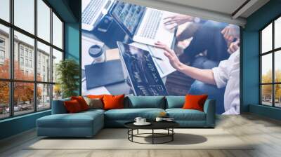 Young coworkers working on laptop computer at office.Woman holding tablet hand and pointing on touch screen with graphs and diagram. Horizontal, blurred background.Cropped. Wall mural