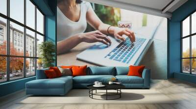 Young woman working at home on modern computer.Girl typing on laptop keyboard while sitting at the wooden table.Concept of young modern people using mobile devices at home.Blurred background. Wall mural