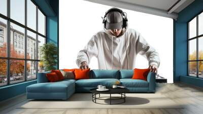 a young man in a white hoodie and grey cap, with headphones on his head playing music from the DJ console against a clean white background. Wall mural