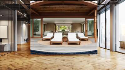 luxurious, modern tropical villa with a wooden exterior and large glass sliding doors. The layout features an expansive wooden deck with three white cushioned lounge chairs positioned around a circula Wall mural