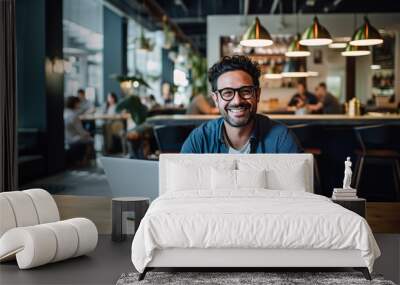 Man working on laptop in cafe, freelancer with computer in cafe, man in glasses smiling looking at the camera Wall mural