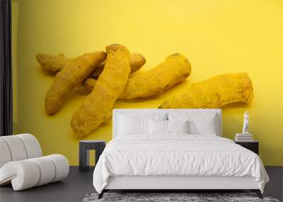 fresh turmeric dry root slices isolated on yellow background Wall mural