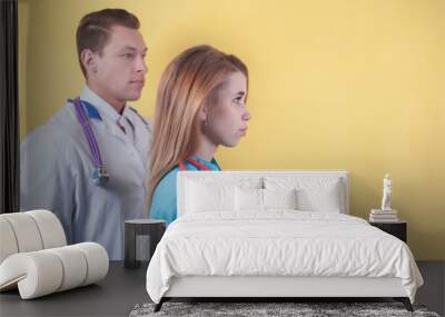 the female doctor and the male doctor look away thoughtfully. yellow background Wall mural