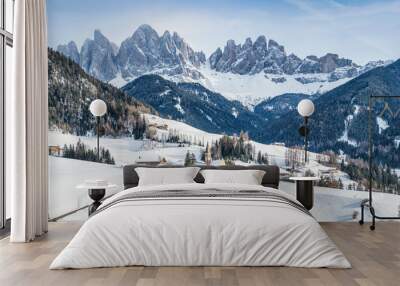 Classic panoramic view of famous Dolomites mountain peaks with the idyllic village Val di Funes and historic Church of St. Magdalena on a scenic sunny day with blue sky in winter, South Tyrol, Italy Wall mural