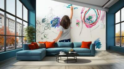 Curly cute little toddler girl painting with paints color and brush on the wall. Works of child Wall mural