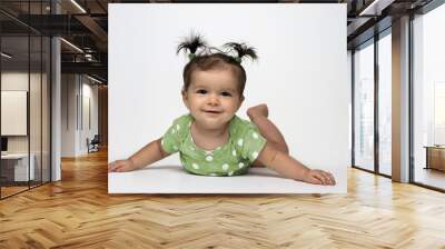 Adorable baby girl in green polka dot onesie lying on stomach Wall mural