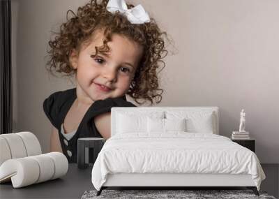 Smiling adorable toddler with curly brown hair cute expression isolated on background Wall mural