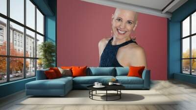 Stylish smiling middle aged over 50 woman survivor with alopecia isolated on pink background Wall mural