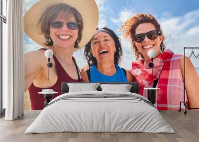 Three laughing women friends  tourists selfie blue sky beach background Wall mural