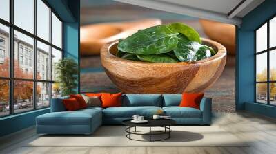   A wooden bowl brims with spinach leaves atop a wooden table alongside another bowl of spinach leaves Wall mural