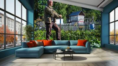 The farmer stands with a shovel in the garden. Preparing the soil for planting vegetables. Gardening concept. Agricultural work on the plantation Wall mural