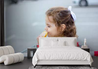 Little girl eating a donut at mall parking. Wall mural