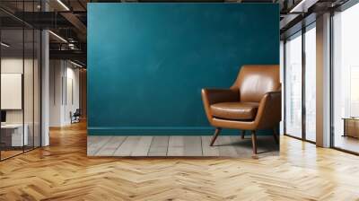 A vintage leather armchair in a room with a teal blue wall and wooden floor. Wall mural