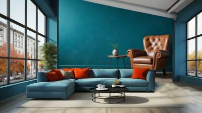 A vintage leather armchair in a room with a teal blue wall and wooden floor. Wall mural