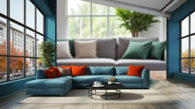 A wooden table is in the foreground with a blurred gray sofa and green plants in the background. Wall mural