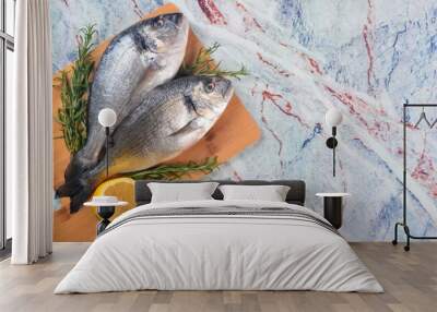 Two Fresh Dorado fish with lemon, onion and rosemary on light marble background, top view Wall mural