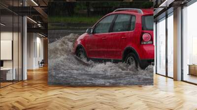 Red car rides in heavy rain on a flooded road Wall mural