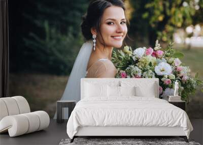 A beautiful bride stands on nature in greenery with a large bouquet. Wedding portrait close-up of the young bride. Wedding photography. Wall mural