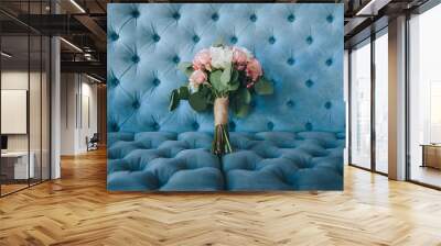 The bride’s wedding bouquet of roses and peonies lies on a blue sofa in a beautiful interior. Photography, concept. Wall mural