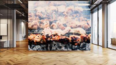 Close up shot of appetizing hot shish kebab on metal skewers prepares on the coals outdoors. Grilling shashlik on barbecue grill. Wall mural