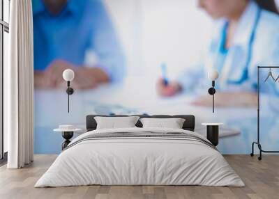 Doctor woman sitting with male patient at the desk Wall mural