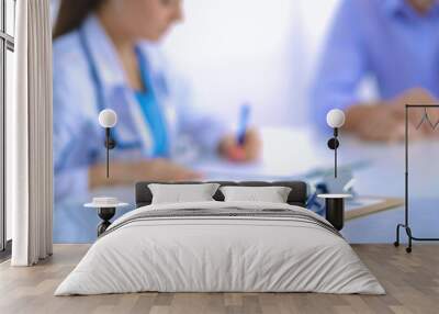 Doctor woman sitting with  male patient at the desk Wall mural