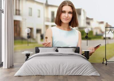 happy woman with keys standing near house Wall mural