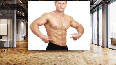 Muscular young man showing abs, isolated o white background Wall mural