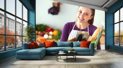 Young woman holding grocery shopping bag with vegetables Standing in the kitchen Wall mural