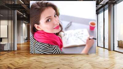 Young woman writes to diary on a white table Wall mural