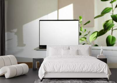 A photo of a laptop on a white desk with a green plant Wall mural