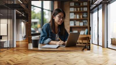 A young positive Asian female college student studying online and doing homework at a coffee shop Wall mural