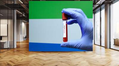 Corona virus or Covid-19 in sierra leone , sample blood tube in hand with sierra leone flag on background Wall mural