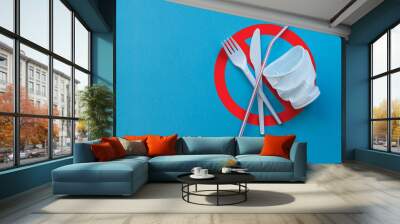 White plastic single tableware on a blue background as a symbol of environmental pollution Wall mural