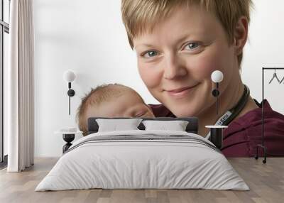 A female nurse cradles a sleeping newborn baby in her arms. Wall mural