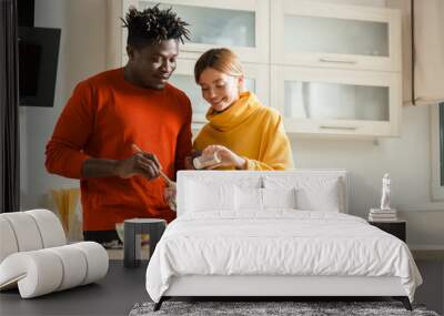 Peaceful couple smiling and adding salt to their salad Wall mural