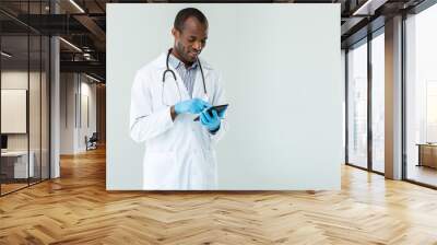 Positive afro american doctor standing against white background Wall mural