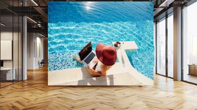 woman using laptop online business remotely near swimming pool. Sexy female blogger browsing laptop online home pool outdoors. Champagne drinking on summer vacations. Online female entrepreneur. Wall mural