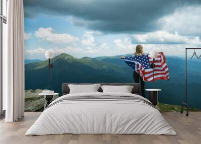 Woman holding USA flag on top of mountain and enjoys the view of the autumn rocks hills. Celebrating Independence Day of America Wall mural