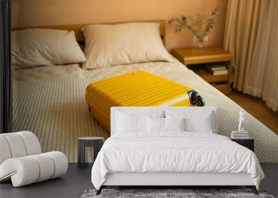 Yellow suitcase on bed indoors entering hotel room for travel, adventure and holiday before leaving for vacation. High quality photo Wall mural