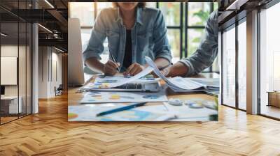 A happy young business woman and male colleagues are working together on laptops in the office, looking at documents. Concept photo, about the passion of a human resources team Wall mural