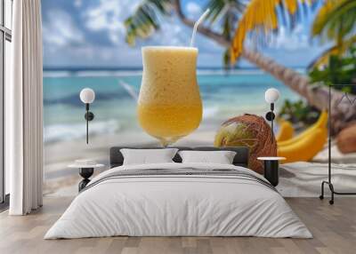 In the glamour magazine photo, a drink and a thick straw, the turquoise ocean in the background is a beautiful beach, on the beach, two coconuts lie behind a glass of smoothies Wall mural