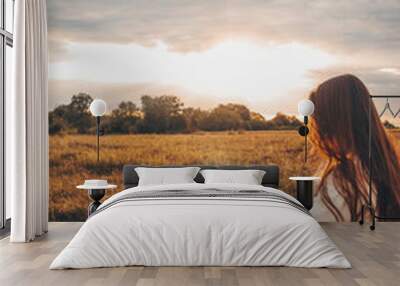 Christian woman holds bible in her hands. Reading the Holy Bible in a field during beautiful sunset. Concept for faith, spirituality and religion. Peace, hope Wall mural