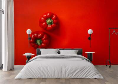 Minimalist image featuring two vibrant red bell peppers placed against a matching red background Wall mural