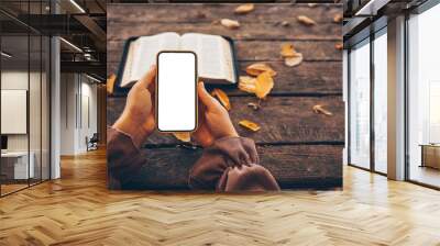 Open bible and phone with isolated screen on wooden background Wall mural