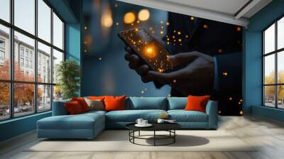 A businessman holding a smartphone with glowing particles on the screen, standing outdoors in an urban environment at night. Wall mural