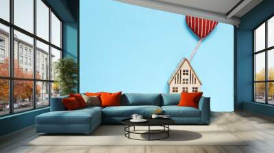 flat lay top view, wooden house with heart flying on a balloon in the shape of a heart, concept of family, home, gift, valentine's day on pastel background Wall mural